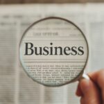 Close-Up of a Magnifying Glass Focusing on the Word Business in a Newspaper
